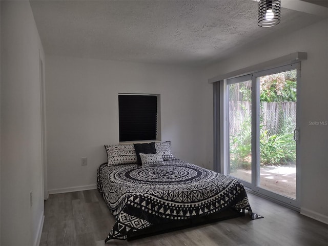 bedroom featuring wood-type flooring, access to exterior, and a textured ceiling