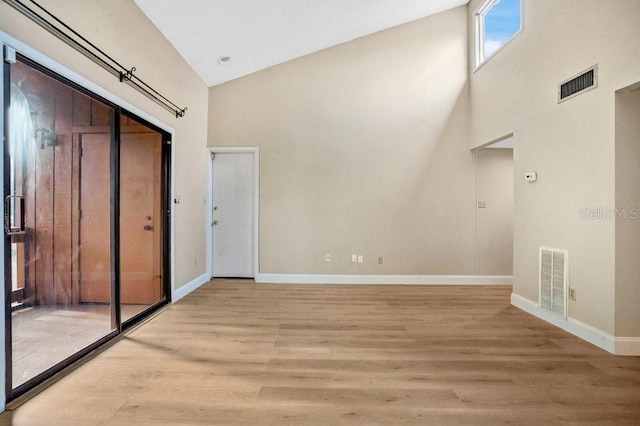 unfurnished bedroom with high vaulted ceiling, a closet, and light hardwood / wood-style floors