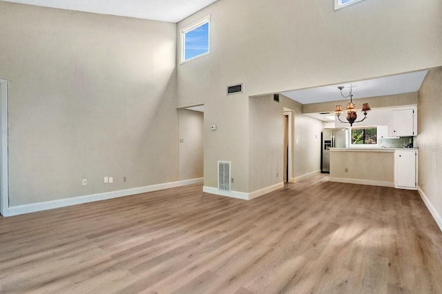 unfurnished living room featuring light hardwood / wood-style floors, a healthy amount of sunlight, and a chandelier