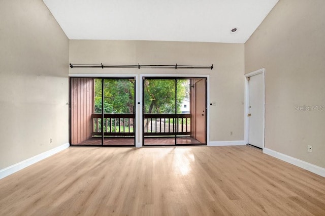 spare room with high vaulted ceiling and light hardwood / wood-style floors