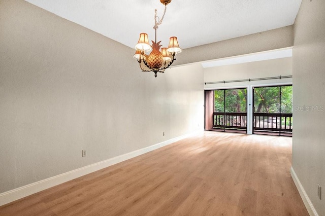 unfurnished room featuring hardwood / wood-style floors and an inviting chandelier