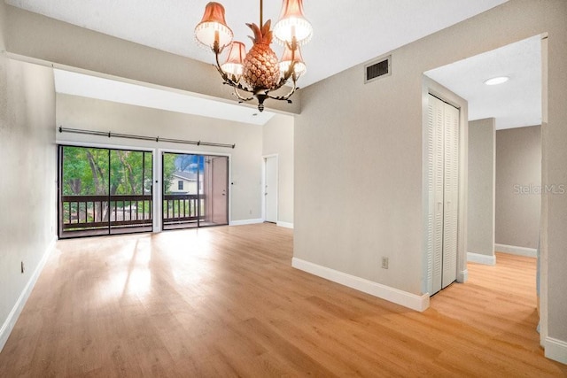 empty room featuring an inviting chandelier and light hardwood / wood-style floors