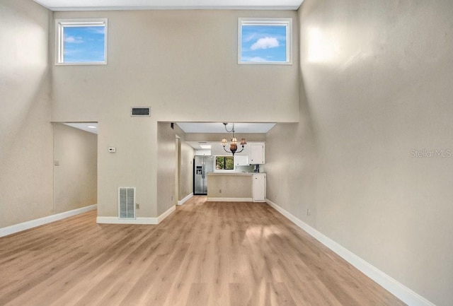 unfurnished living room featuring light hardwood / wood-style flooring and a notable chandelier