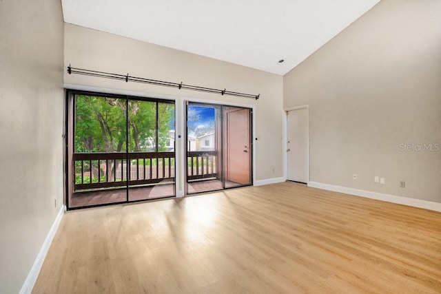 empty room featuring high vaulted ceiling and light hardwood / wood-style flooring