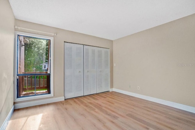 unfurnished bedroom with a closet, a textured ceiling, and light hardwood / wood-style floors