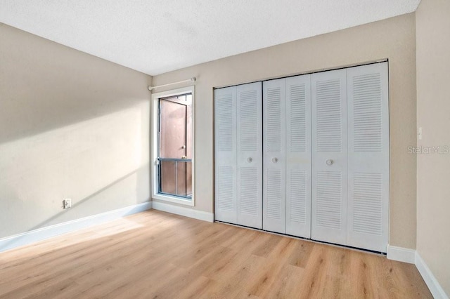 unfurnished bedroom featuring light hardwood / wood-style floors, a textured ceiling, and a closet