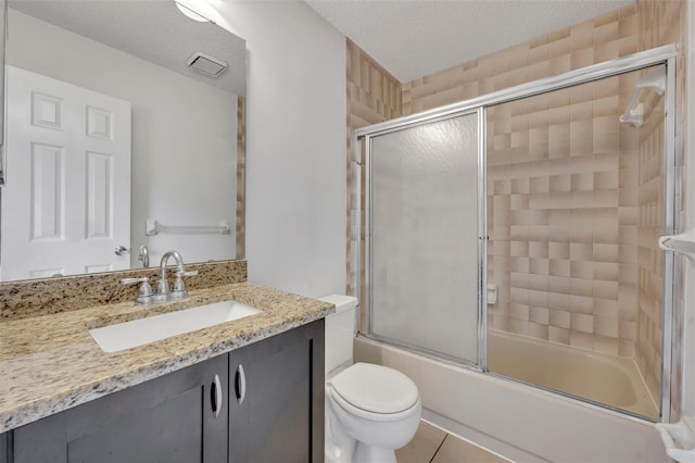 full bathroom with bath / shower combo with glass door, vanity, toilet, tile patterned floors, and a textured ceiling