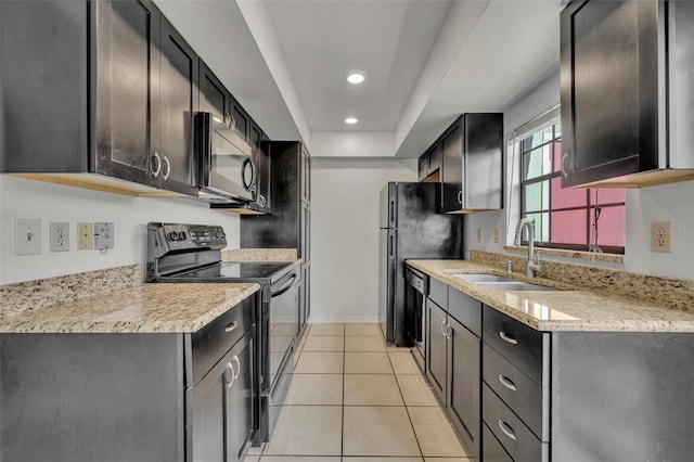 kitchen with sink, light stone counters, light tile patterned floors, a tray ceiling, and black appliances