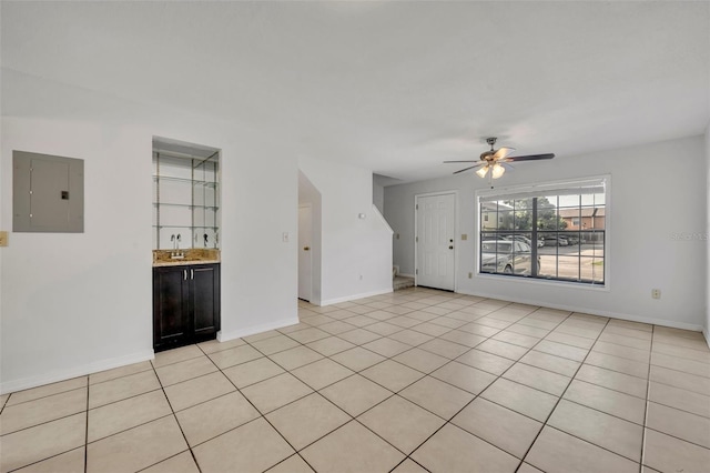 unfurnished living room with light tile patterned flooring, sink, electric panel, and ceiling fan