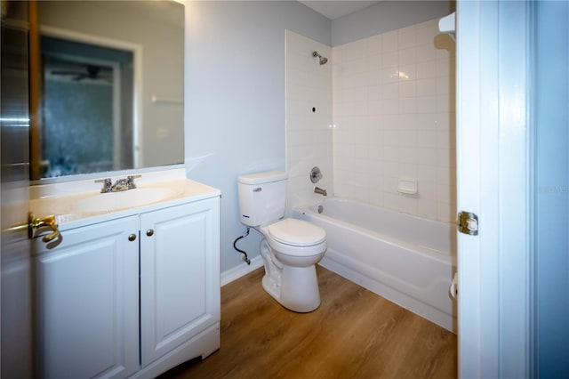 full bathroom featuring hardwood / wood-style floors, tiled shower / bath, vanity, and toilet