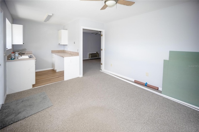 unfurnished living room with ceiling fan, carpet flooring, and sink