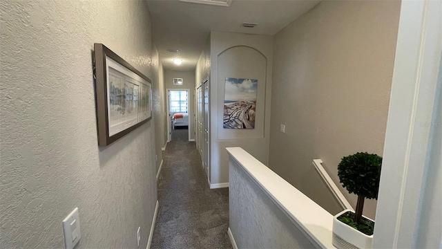 hallway featuring dark colored carpet