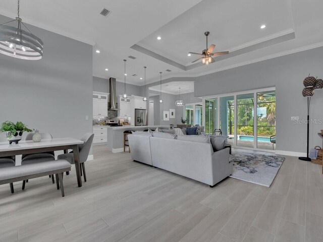 living room featuring ceiling fan, ornamental molding, and a tray ceiling