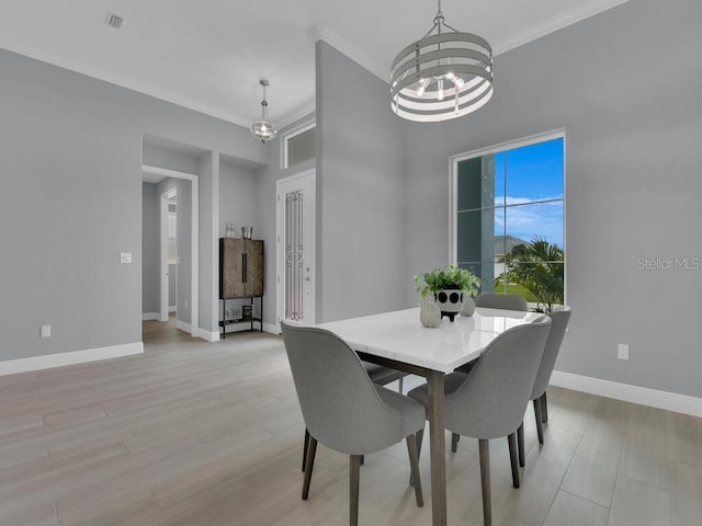 dining area featuring ornamental molding, light hardwood / wood-style floors, and a chandelier