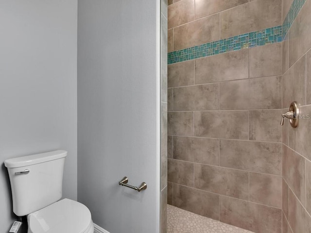 bathroom featuring a tile shower and toilet