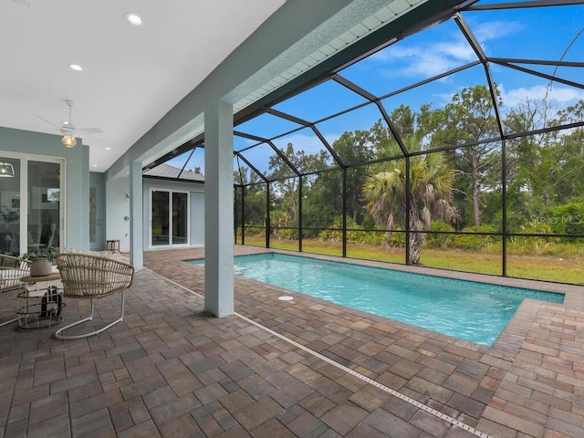 view of swimming pool with a patio, ceiling fan, and glass enclosure