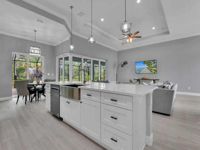 kitchen with pendant lighting, a raised ceiling, sink, white cabinetry, and a kitchen island with sink