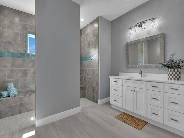 bathroom with hardwood / wood-style flooring, vanity, and tiled shower