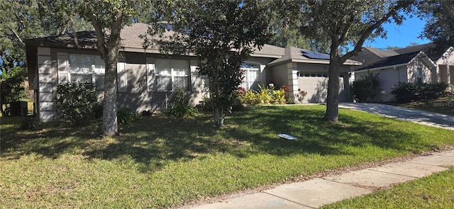 view of front of house with solar panels, a garage, and a front lawn