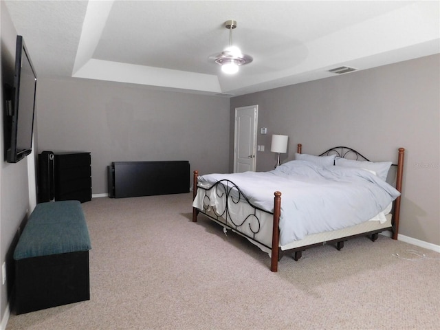 bedroom featuring a raised ceiling, ceiling fan, and carpet flooring