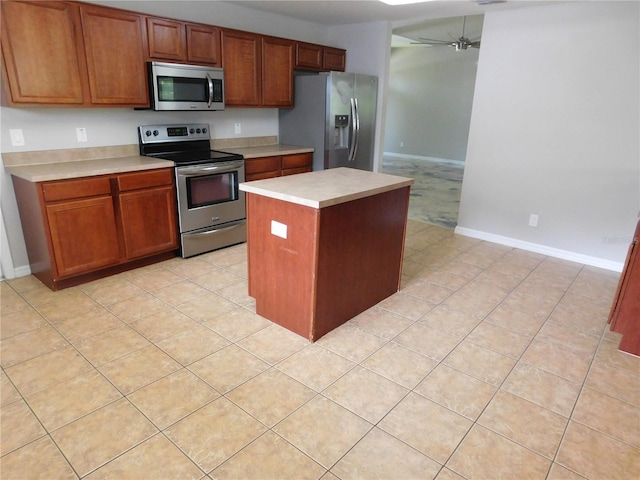 kitchen featuring appliances with stainless steel finishes, a center island, light tile patterned floors, and ceiling fan