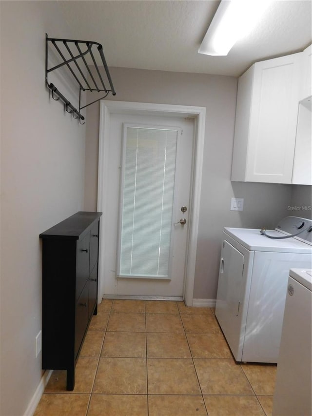 laundry room with cabinets, light tile patterned floors, and separate washer and dryer