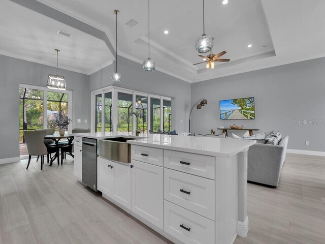 kitchen with sink, dishwasher, a center island with sink, a raised ceiling, and light hardwood / wood-style floors