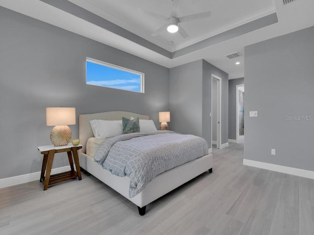 bedroom with a tray ceiling, ceiling fan, and light wood-type flooring