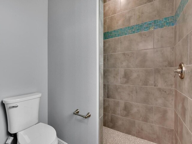 bathroom featuring tiled shower and toilet