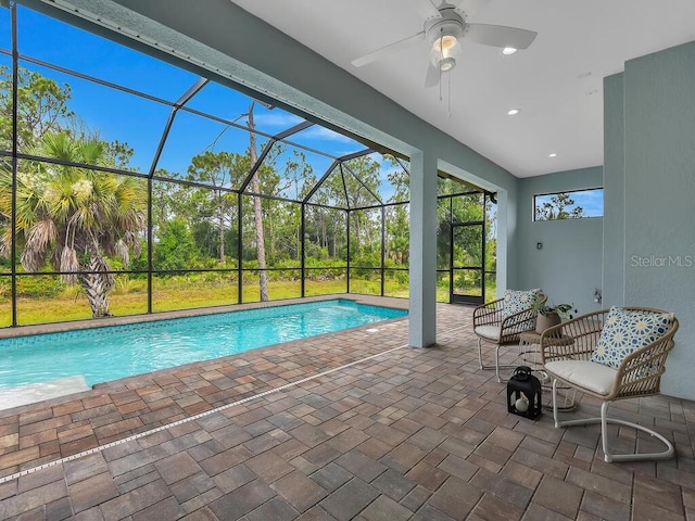 view of swimming pool with a patio area, ceiling fan, and glass enclosure