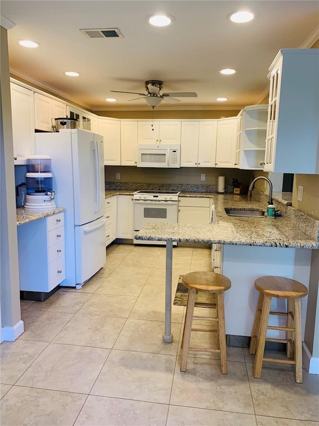 kitchen with kitchen peninsula, white appliances, light stone counters, and sink