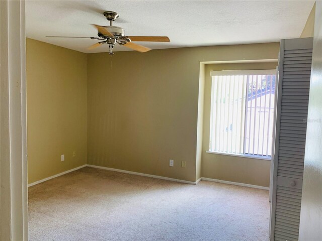 carpeted empty room with ceiling fan and a textured ceiling