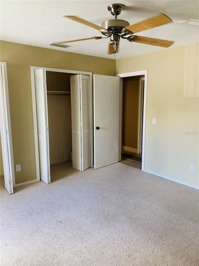 unfurnished bedroom featuring ceiling fan, light colored carpet, a closet, and a textured ceiling