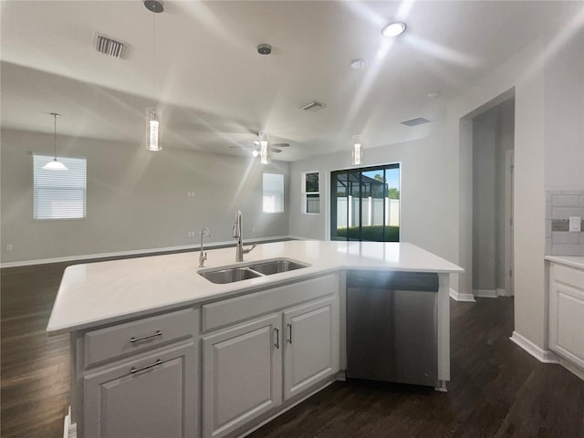 kitchen featuring stainless steel dishwasher, ceiling fan, sink, a center island with sink, and dark wood-type flooring