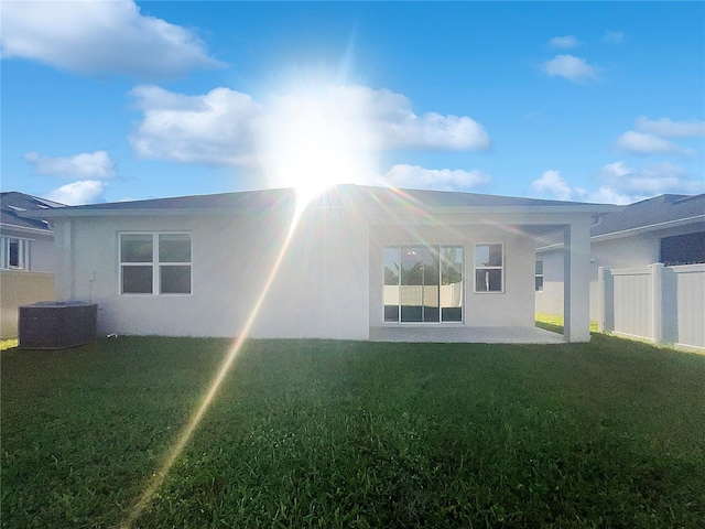 rear view of house with central air condition unit and a yard