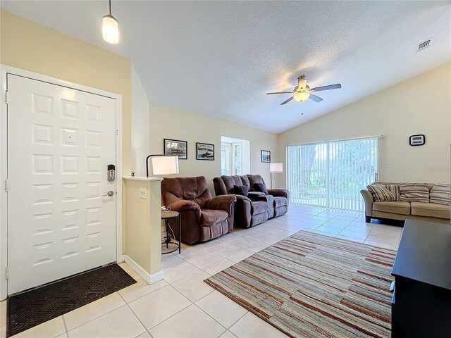 tiled living room with a textured ceiling, vaulted ceiling, and ceiling fan