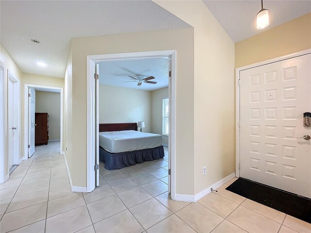 entryway featuring a textured ceiling, ceiling fan, and light tile patterned floors