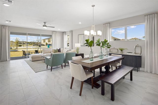 dining room with ceiling fan with notable chandelier and a wealth of natural light