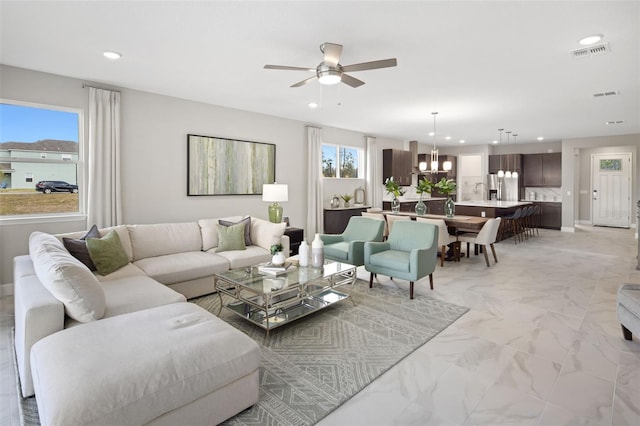 living room featuring ceiling fan with notable chandelier