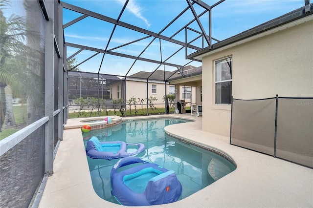 view of pool featuring an in ground hot tub, a patio area, and glass enclosure