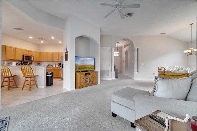 carpeted living room featuring lofted ceiling and ceiling fan with notable chandelier