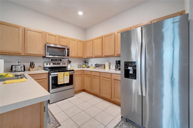 kitchen featuring light tile patterned flooring, appliances with stainless steel finishes, and light brown cabinets