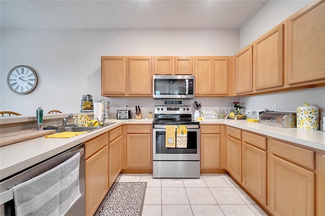 kitchen featuring appliances with stainless steel finishes, sink, light tile patterned floors, and light brown cabinetry