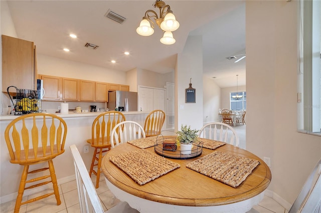 dining area with lofted ceiling, light tile patterned floors, and a notable chandelier