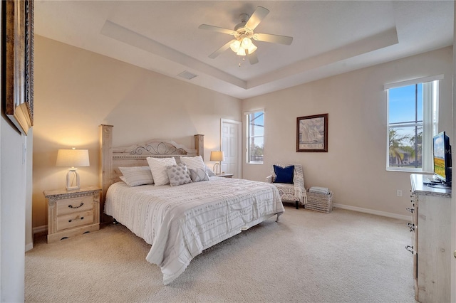 carpeted bedroom with ceiling fan and a tray ceiling