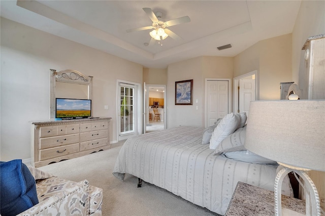 carpeted bedroom featuring ceiling fan and a raised ceiling