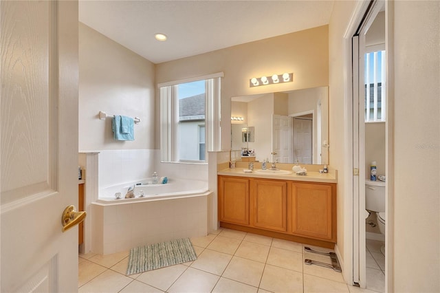 bathroom with a relaxing tiled tub, vanity, tile patterned flooring, and toilet