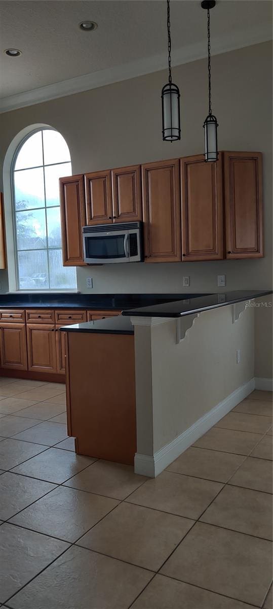 kitchen with crown molding, hanging light fixtures, and light tile patterned floors