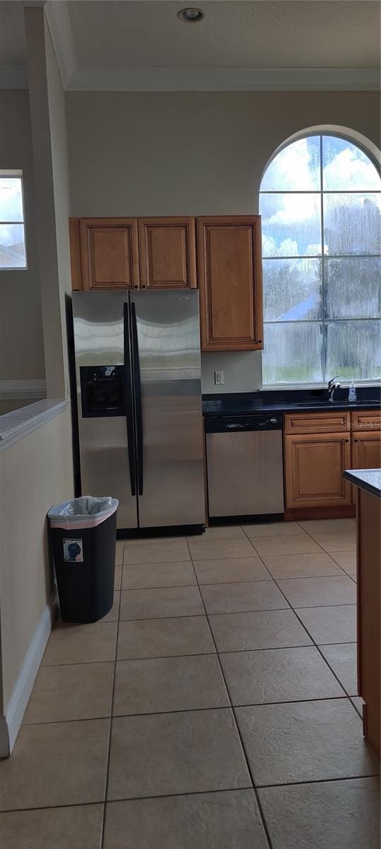 kitchen featuring sink, ornamental molding, stainless steel appliances, and light tile patterned flooring