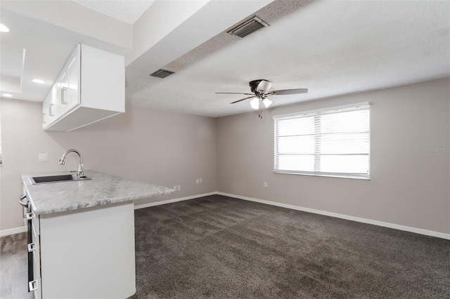 kitchen with white cabinetry, sink, a textured ceiling, and dark colored carpet